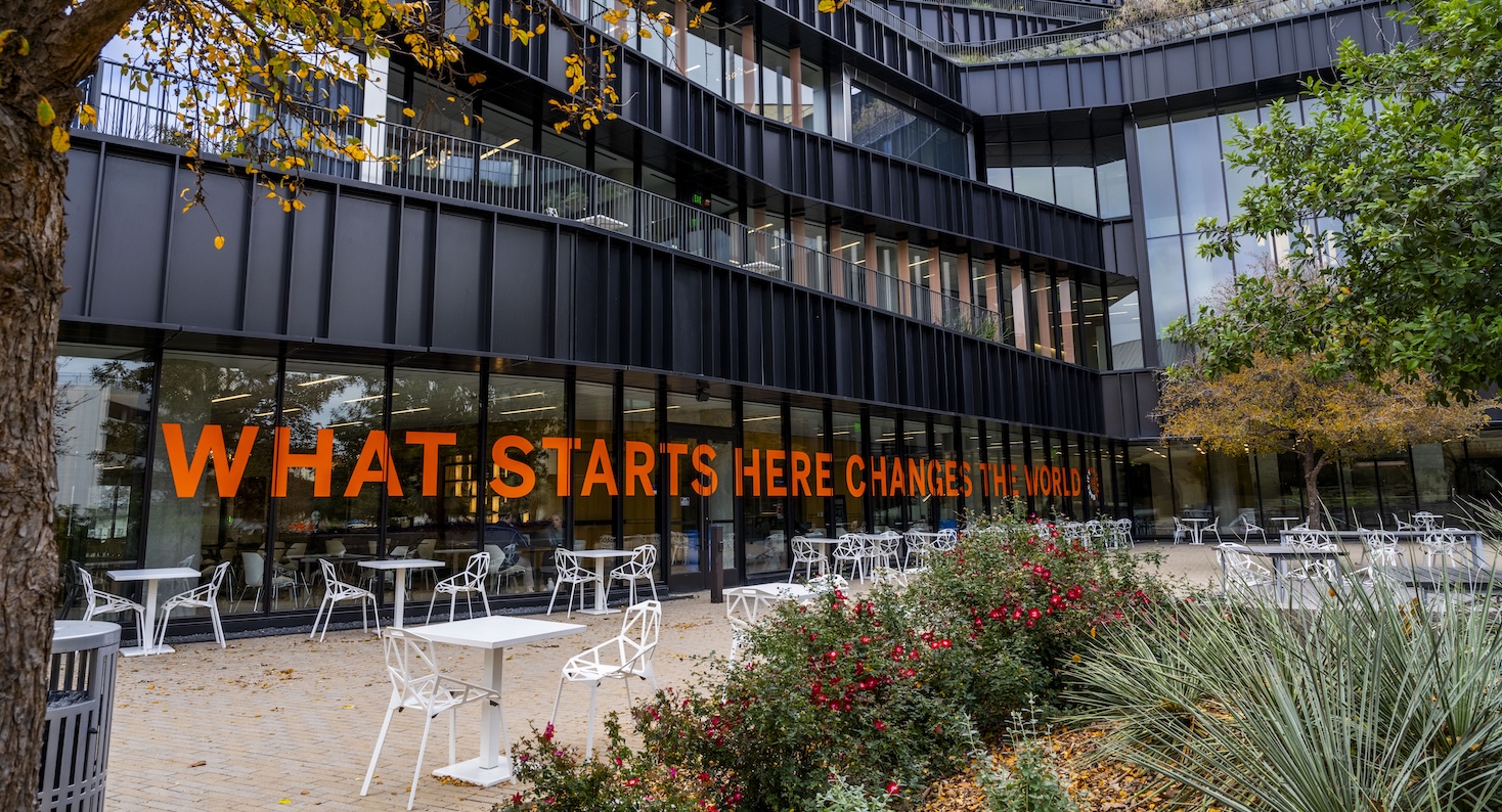 UT Austin slogan, What Starts Here Changes the World, displayed across windows of campus building