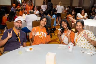 Four people sitting and showing “hook-em” hand signs