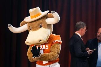 Hook ‘Em mascot standing on stage with two people behind