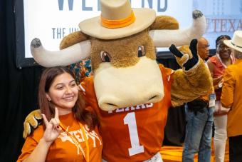 Hook ‘Em mascot posing with someone and showing Hook ‘Em hand signs