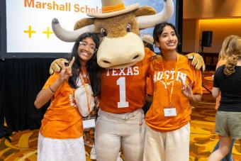 Hook ‘Em mascot posing with two people and showing Hook ‘Em hand signs