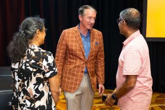 UT Austin President Jay Hartzell chatting with two people