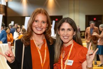 Two people smiling at camera and showing hook ‘em hand signs