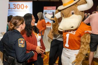 Hook ‘Em mascot chatting with two people