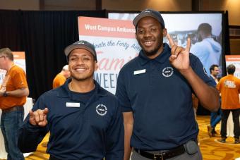 Two people smiling at camera and showing hook ‘em hand signs